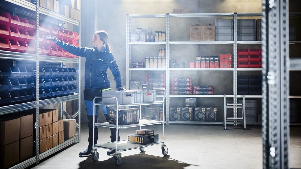 En kvinna sorterar varor i ett lager med hjälp av lagringsutrustning från Cowab. Foto