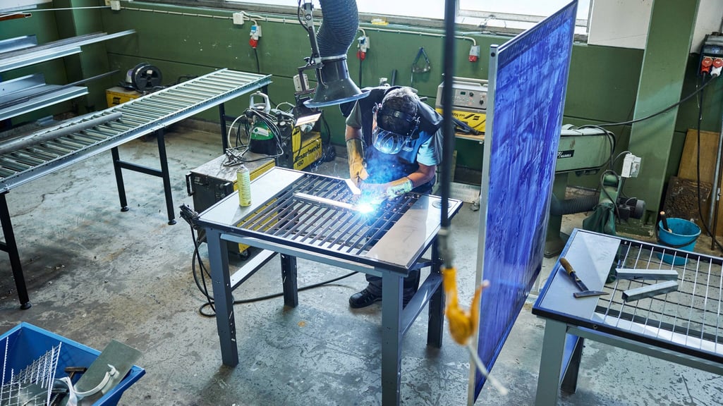 Mann sveiser på verksted. Sveiseskjerm fra Cowab.
