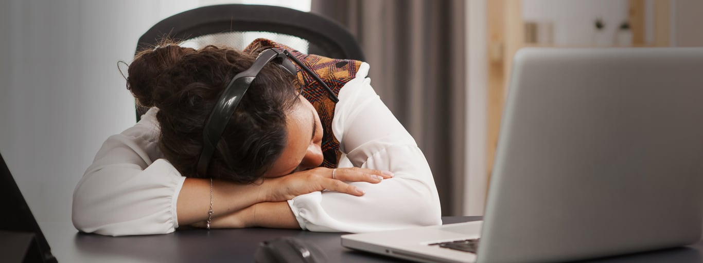 En kvinna som sover framför en datorskärm. Foto