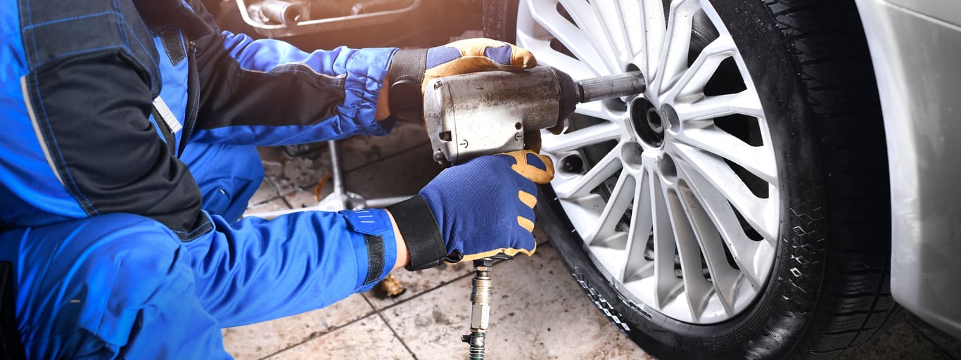 Person skifter dekk på bil. Foto