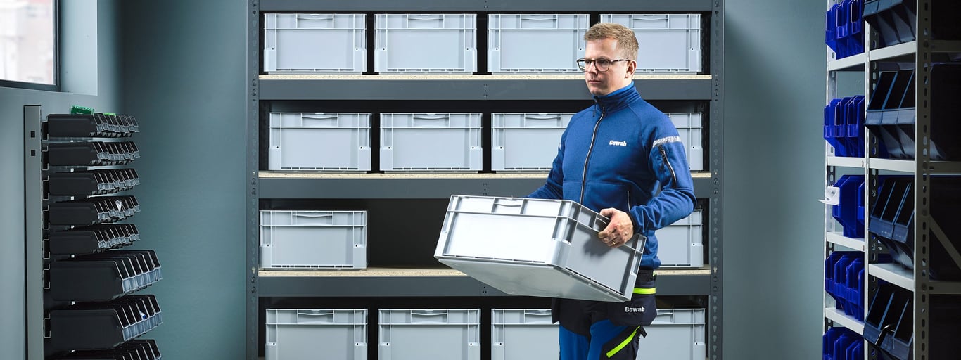 Mann sorterer esker på lager. Foto
