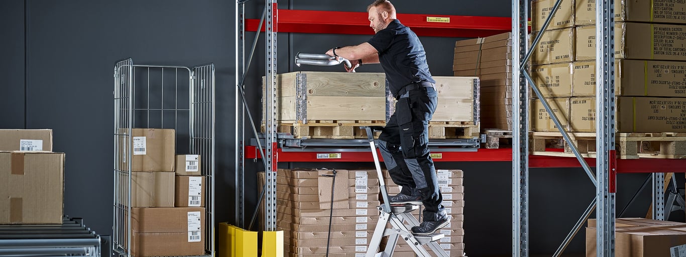 Mann klatrer opp stige på lager. Lagerutstyr fra Cowab. Foto
