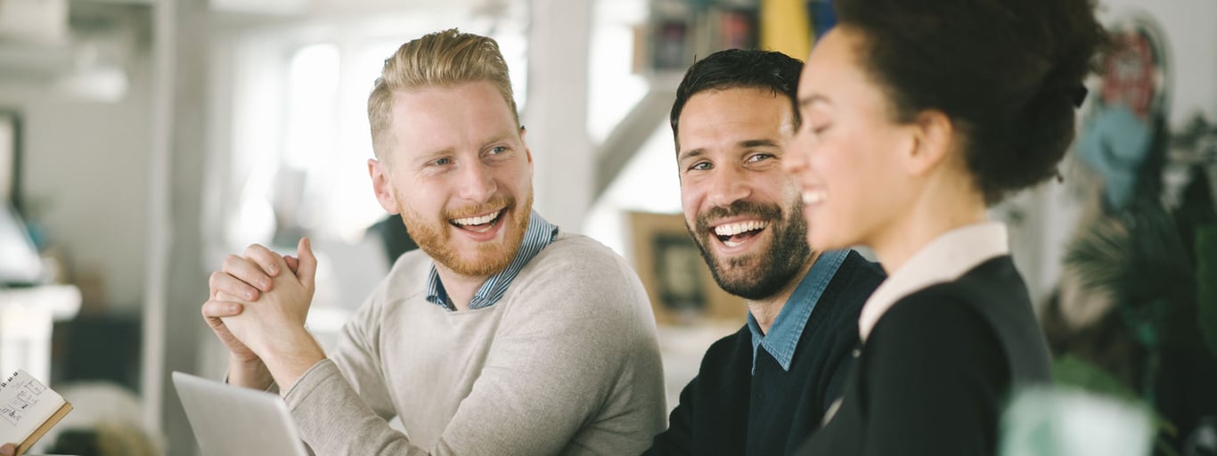 Smilende kollegaer snakker sammen på jobb. Foto