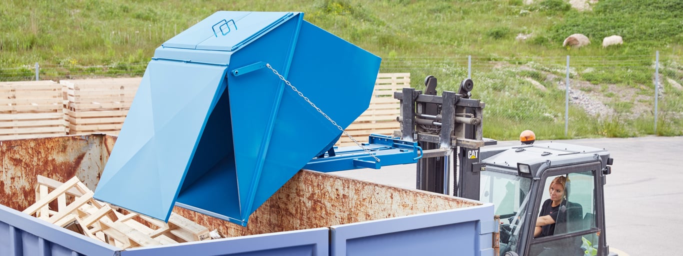 Blå tippcontainer på arbetsplats utomhus. Foto
