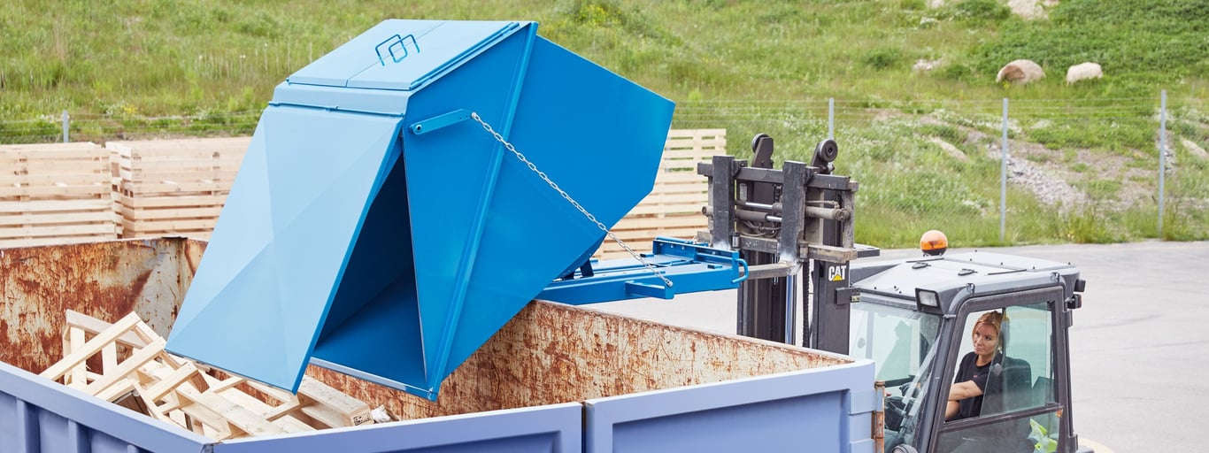 Blå tippcontainer på arbetsplats utomhus. Foto