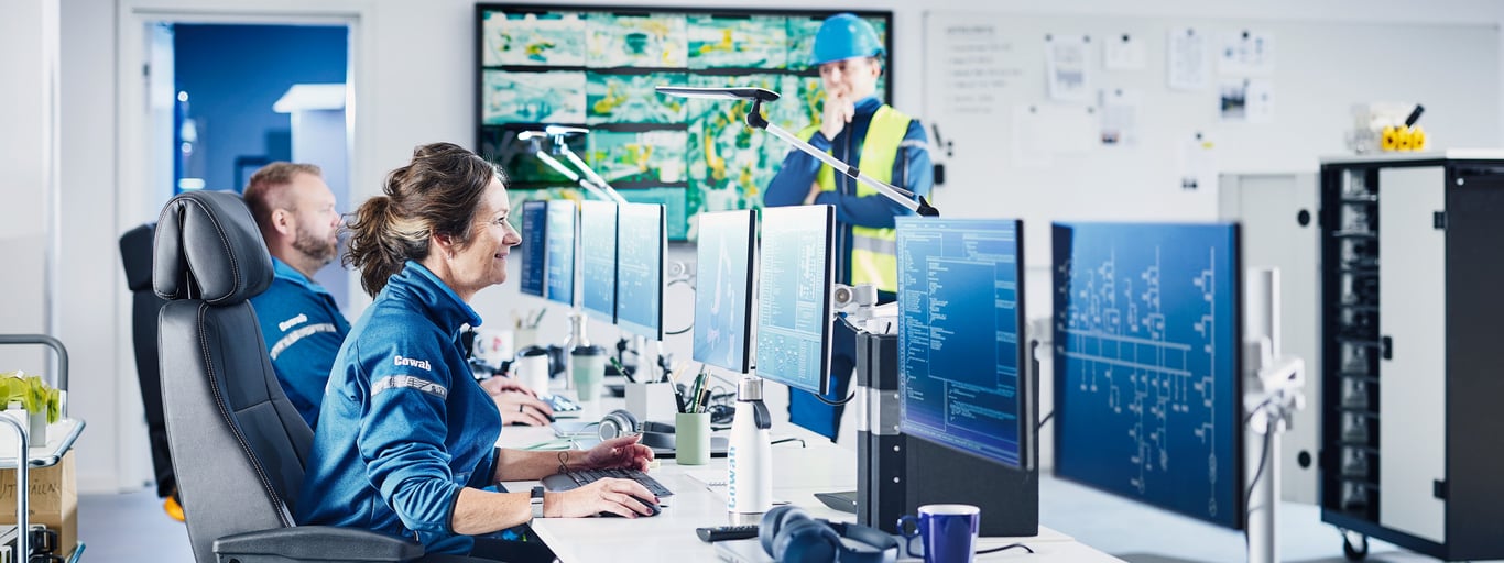 To personer sitter i et kontrollrom. Foto