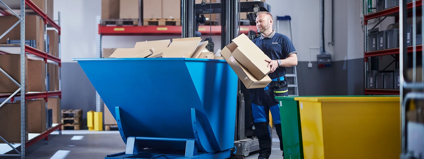 Man på lager med blå tippcontainer från Cowab. Foto