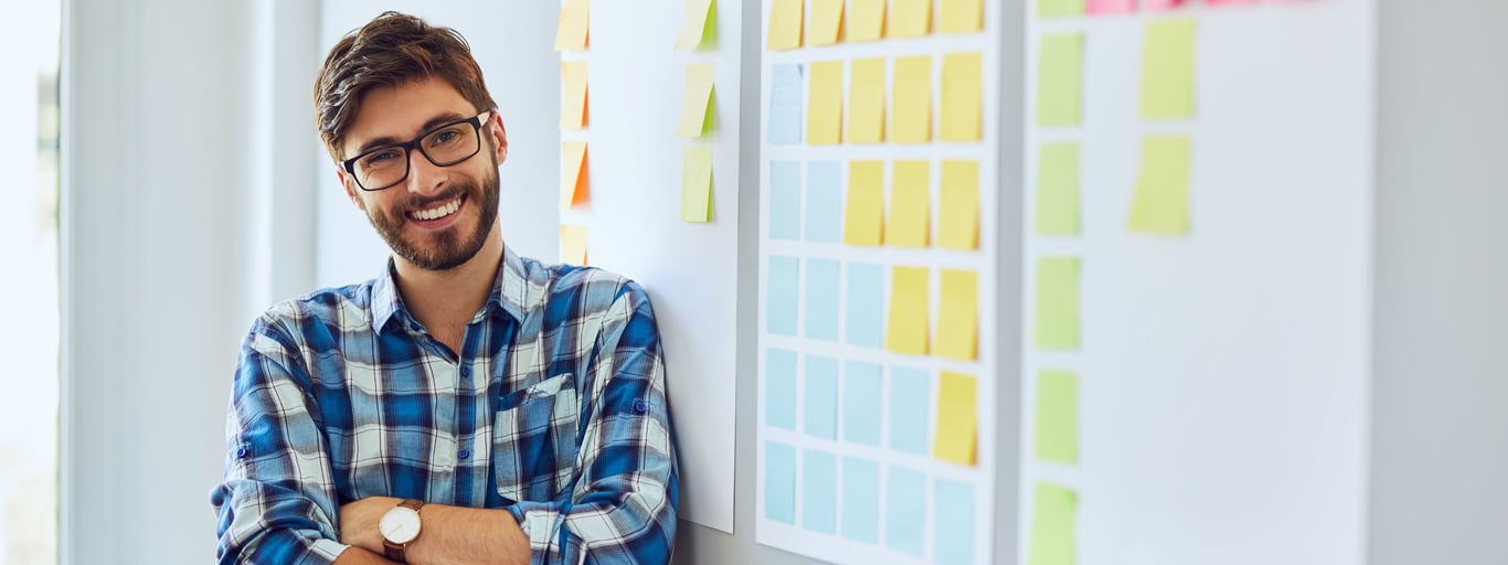 Man lutar sig mot whiteboard med post-it-lappar. Foto