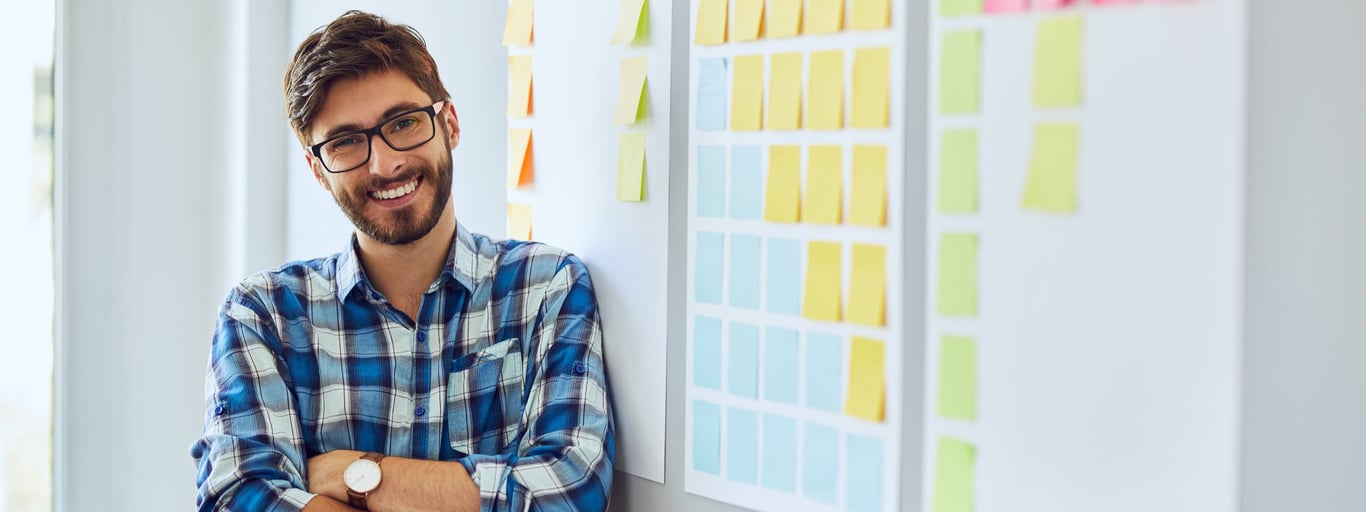 Smilende mann med whiteboard og post-it-lapper. Foto