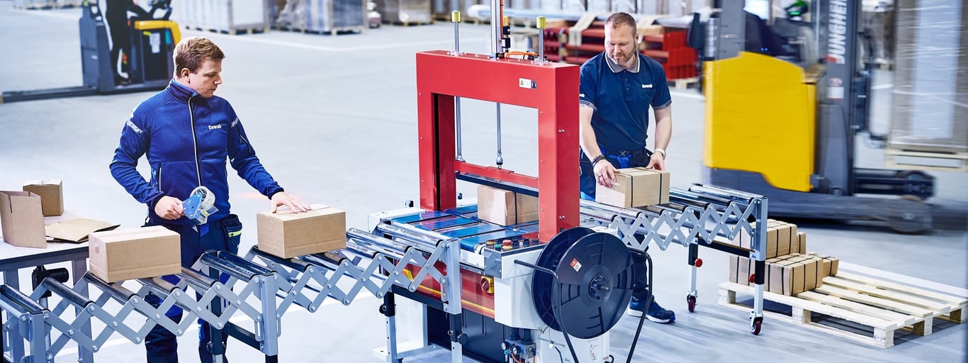 To menn ved stroppemaskin fra Cowan på lager. Foto