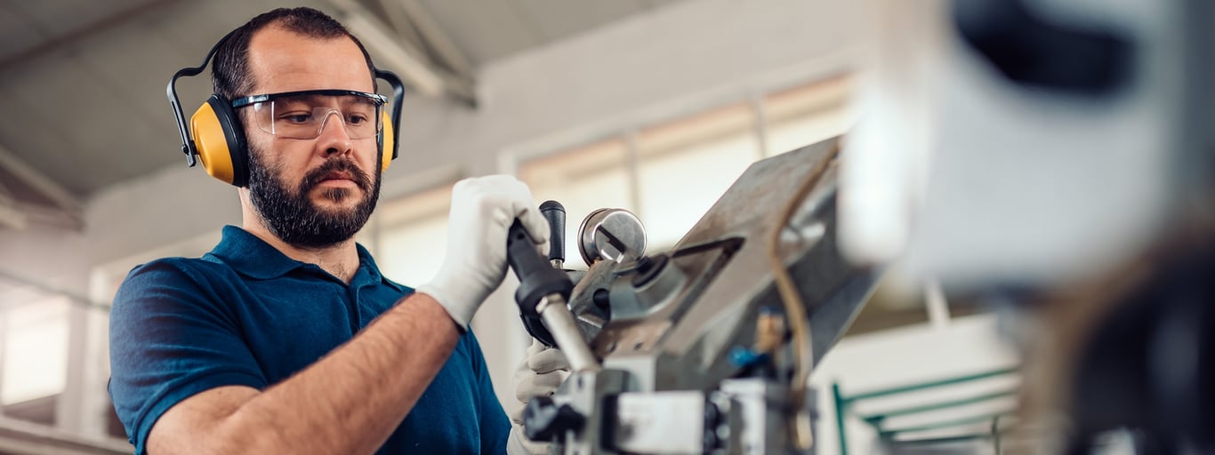 Man med hörselskydd på jobbet. Foto