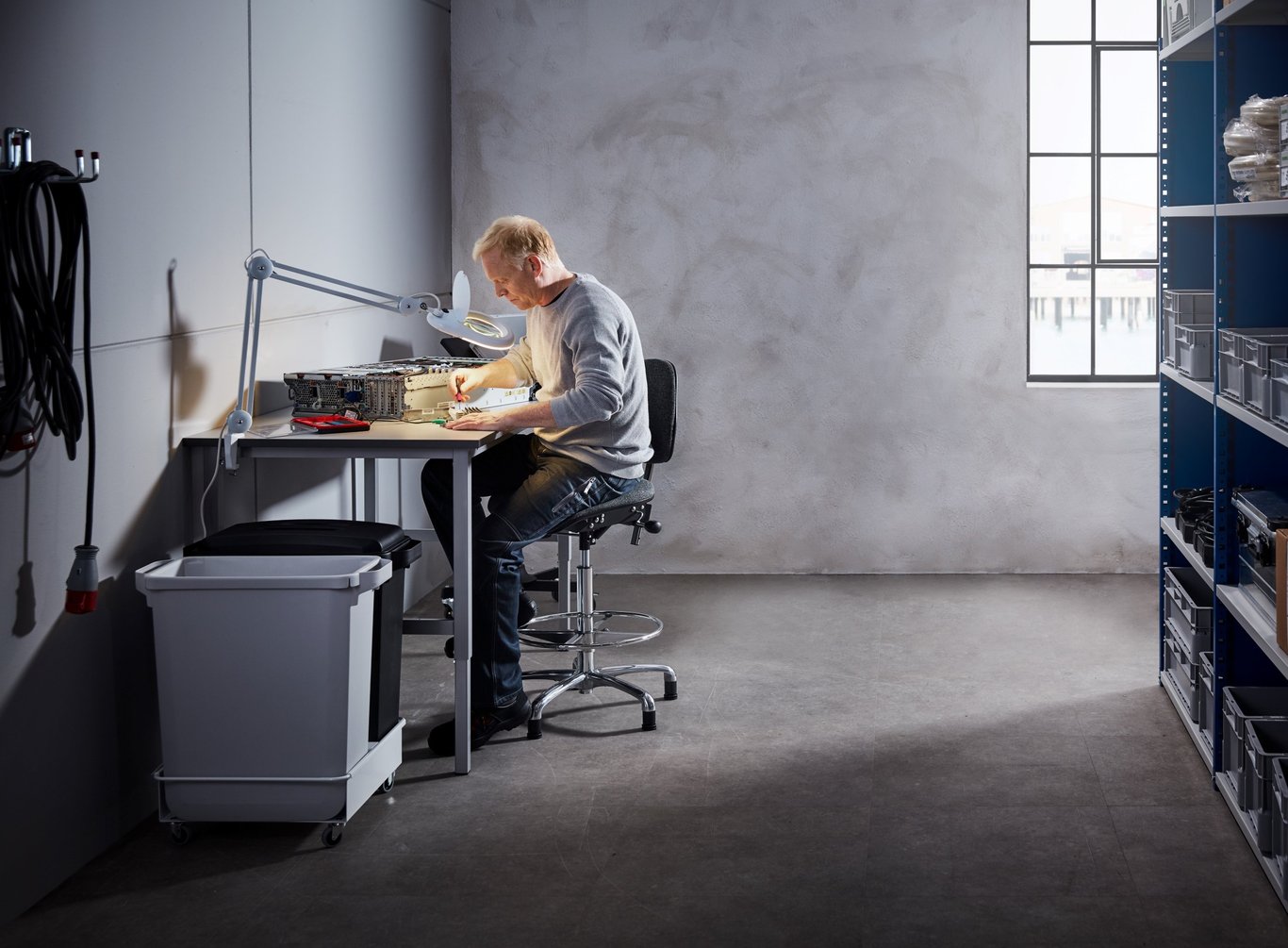 Mann arbeider fokusert ved arbeidsbenk. Foto
