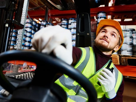 Ansatt styrer maskin på lager. Foto