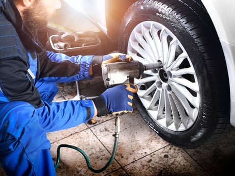 Person skifter dekk på bil. Foto