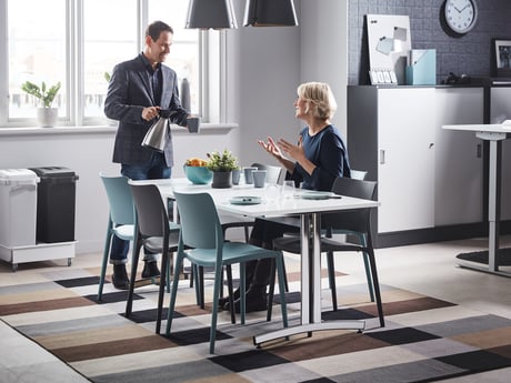 Mann og kvinne prater i kantine. Foto