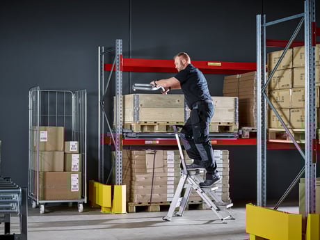 Mann klatrer opp stige på lager. Lagerutstyr fra Cowab. Foto