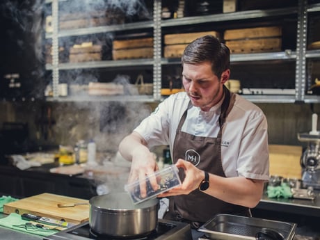 Mann lager mat på Mathallen i Tromsø med innredning fra Cowab. Foto