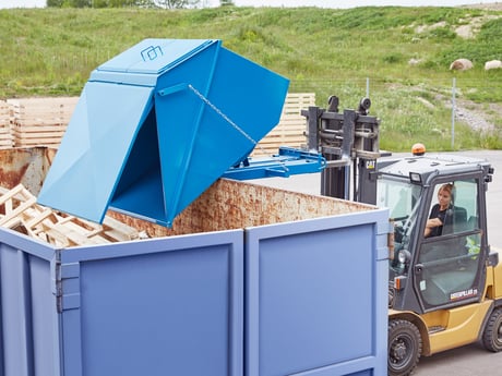 Blå tippcontainer på arbetsplats utomhus. Foto