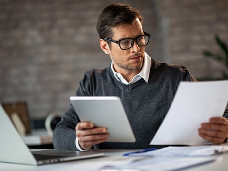 Mann leser konsentrert dokumenter. Foto