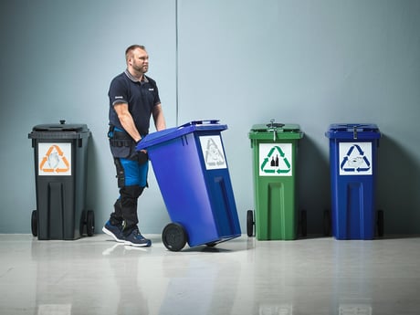 Mann triller på avfallsbeholder. Foto