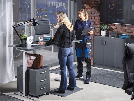 To ansatte ved et hev- og senkbart skrivebord fra Cowab. Foto