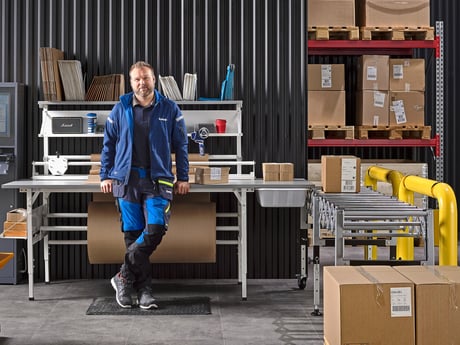 Mann står ved pakkebord fra Cowab. Foto