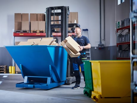 Man på lager med blå tippcontainer från Cowab. Foto