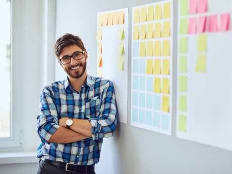 Man lutar sig mot whiteboard med post-it-lappar. Foto