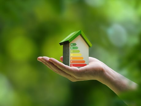 En hand håller ett litet hus. Energiförbrukning Cowab