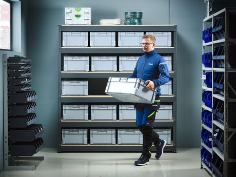 Mann sorterer esker på lager. Foto