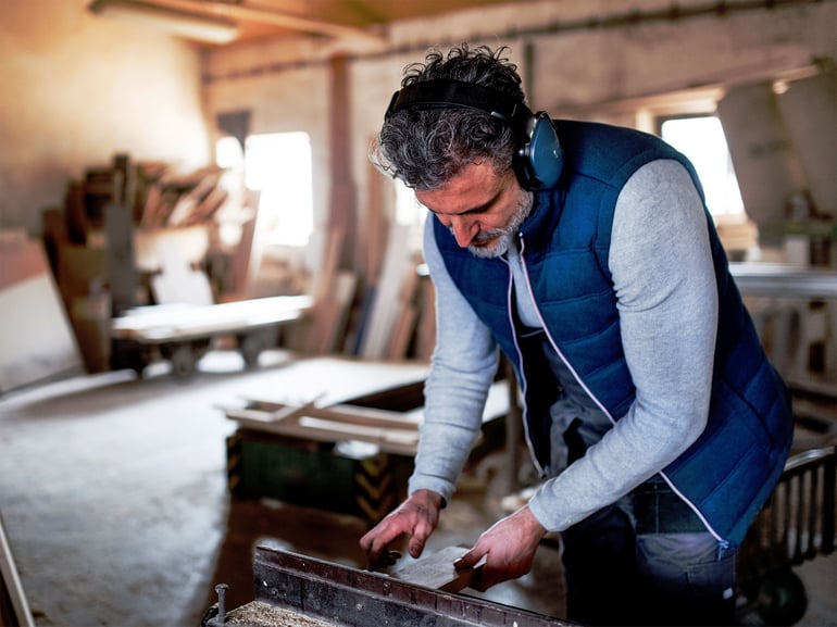 Mann med hodetelefoner på verksted. Foto