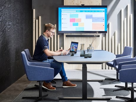 En mann som sitter ved datamaskinen sin i et møterom